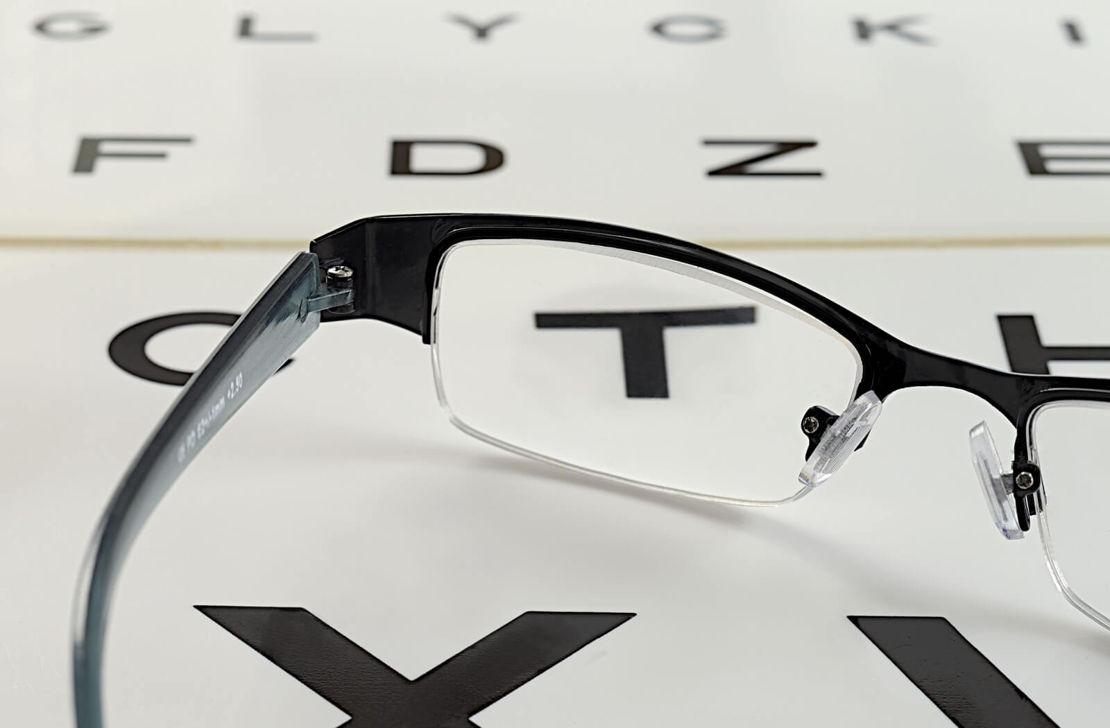 Prescription eyeglasses resting on an eye chart during a vision test.