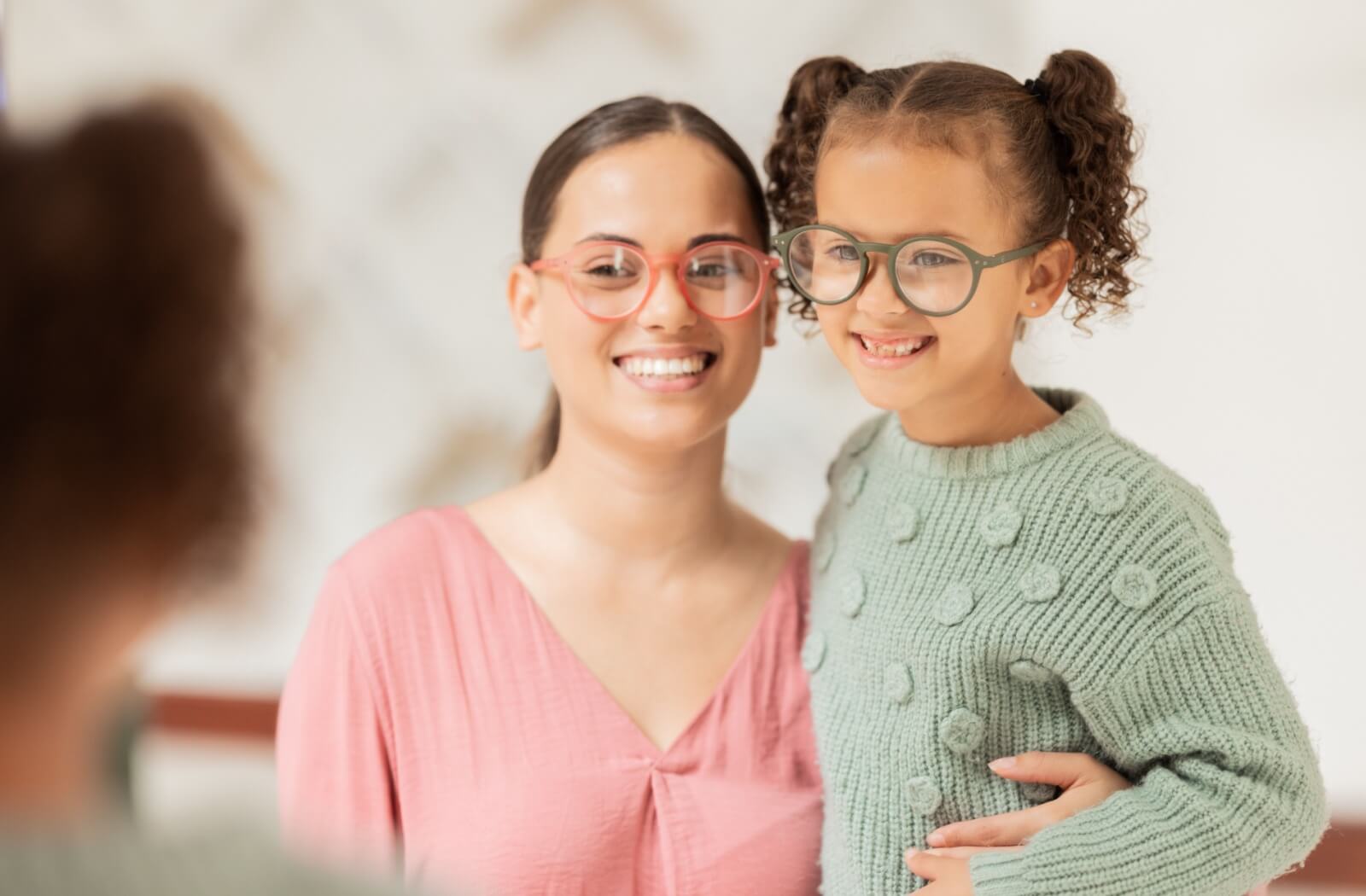 Parent and child smiling together while wearing eyeglasses.