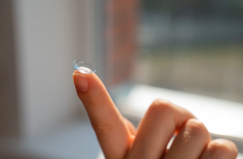 A close-up of a clear soft contact lens properly balanced on a person's fingertip for inspection.